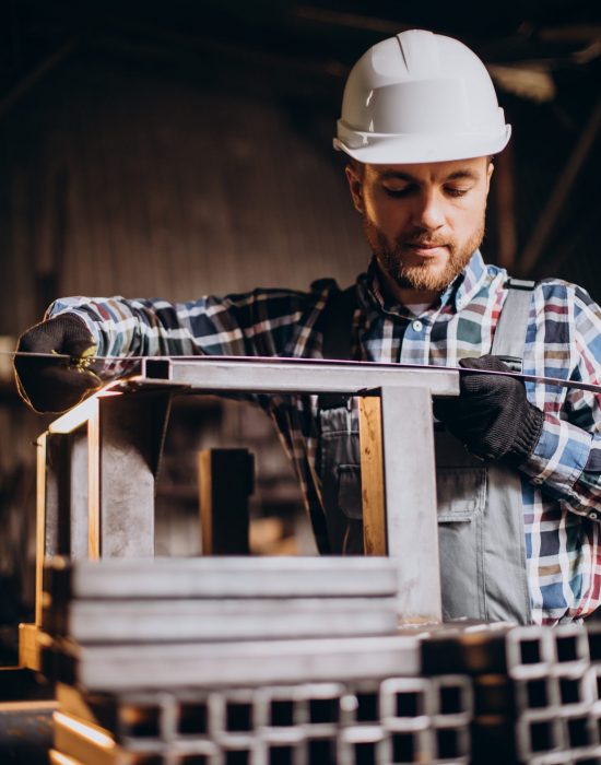 Workman wearing har hat with measuring ruler at factory